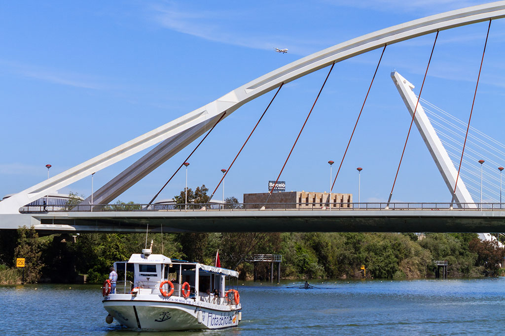 Un barco cruza el Puente de la Barqueta en el río Guadalquivir